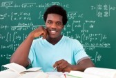 21669033-young-african-man-studying-with-a-lot-of-books-sitting-in-front-of-blackboard